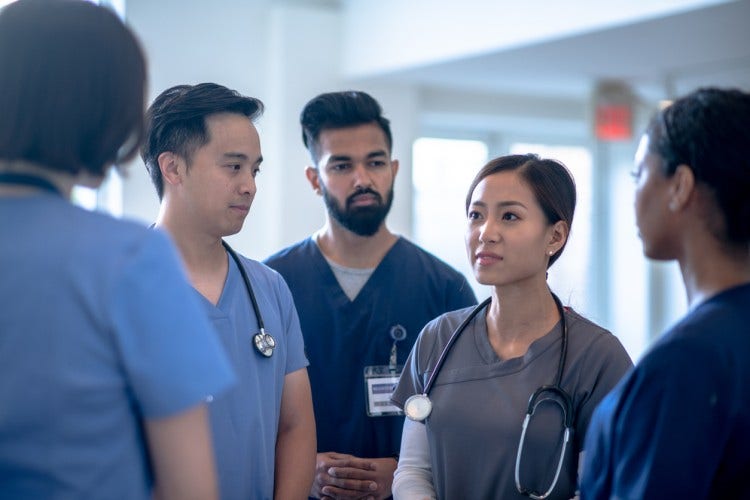 A group of nurses talking in a hospital hallway.