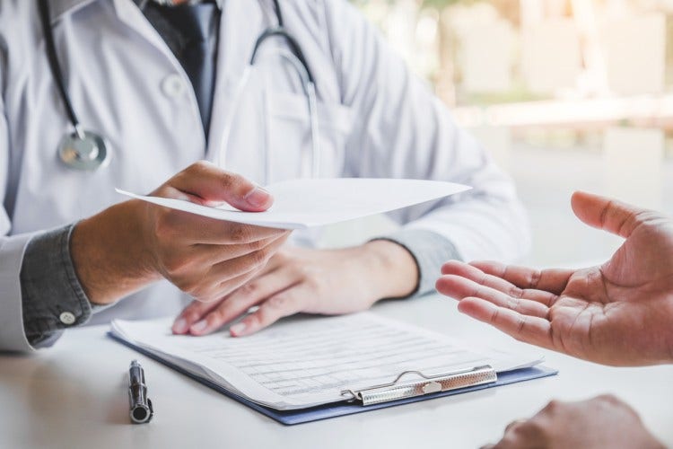 A nurse practitioner prescribing medication hands a written prescription to a patient.