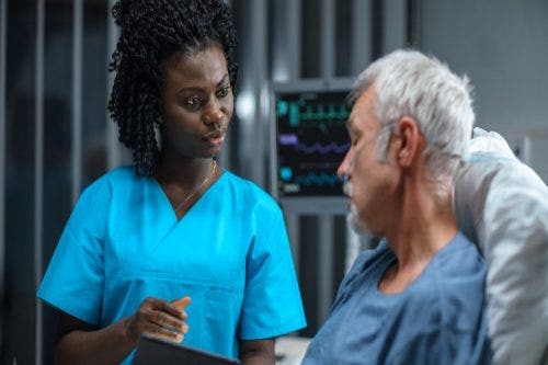 A nurse discusses treatment options with a patient in a hospital bed.