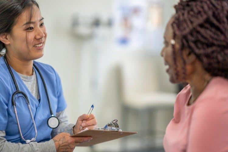 A smiling nurse takes down a patient’s information on a clipboard.