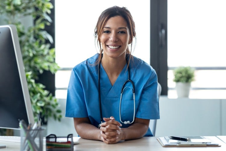 A smiling nurse stands at an intake desk.