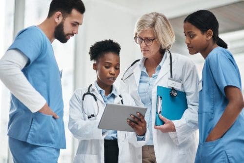 A group of caregivers discuss a treatment plan displayed on a tablet.