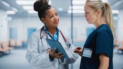 An APRN discusses a treatment plan with a colleague.