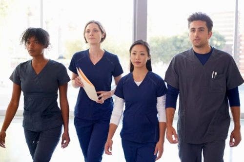 Four nurses walk through a hospital corridor.
