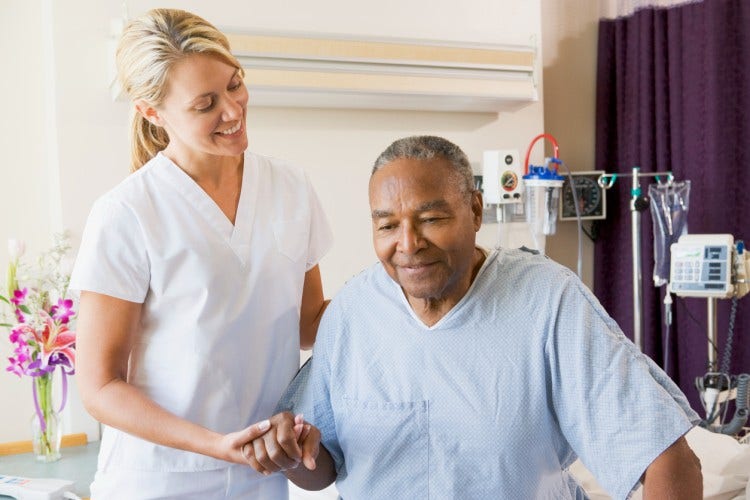 A nurse practitioner helps a patient stand up.