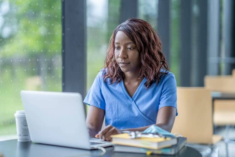 A nurse using a home laptop to pursue continuing education credits.
