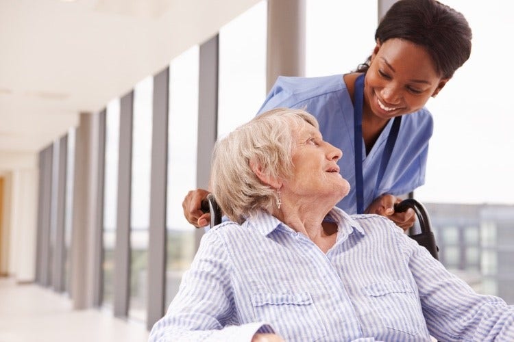 Nurse pushing patient in a wheelchair in a medical office