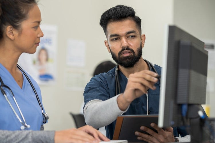 A nurse manager goes over a schedule with a nursing team member.