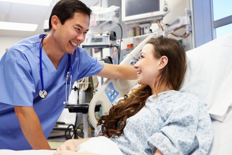A nurse consults with a patient in an ER bed.